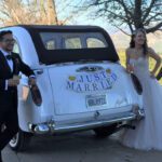 Newly married couple taking a picture from the back of a London Taxi cab.