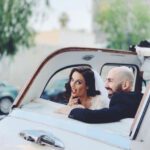 Goofy glamorous couple in rear seat of London Taxi with top down