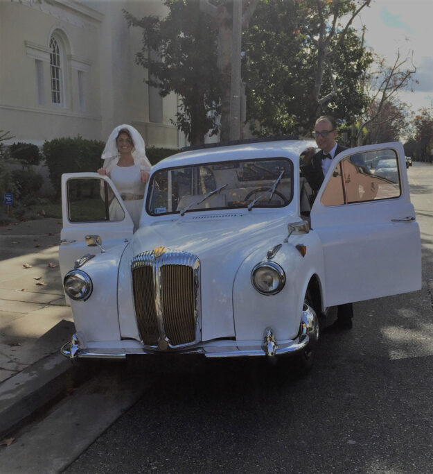 Newlyweds getting into London taxi cab on either side