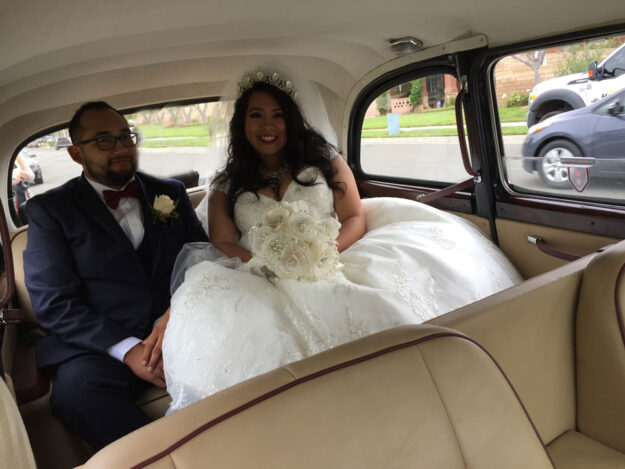 Newlyweds sitting in rear passenger seat of London taxi smiling