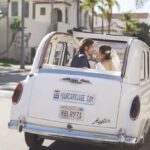 Newlyweds gazing into each other's eyes in back of London taxi with top down
