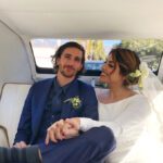 Newlyweds sitting in back of London taxi holding hands