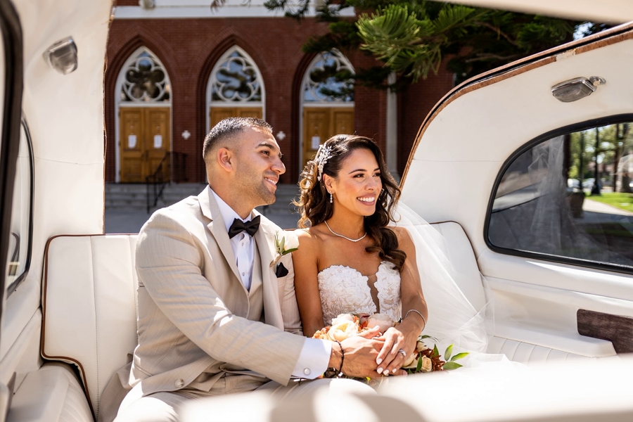 Newlyweds in back seat of Taxi car smiling as they look out the window