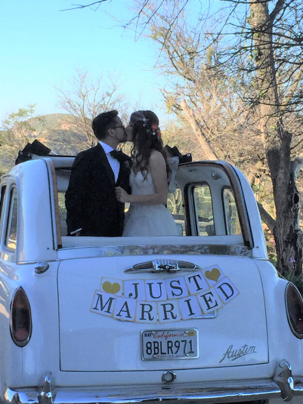 Wedding couple kissing standing in the back of a London Taxi cab.