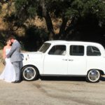 Wedding couple holding each other in front of a London Taxi cab.